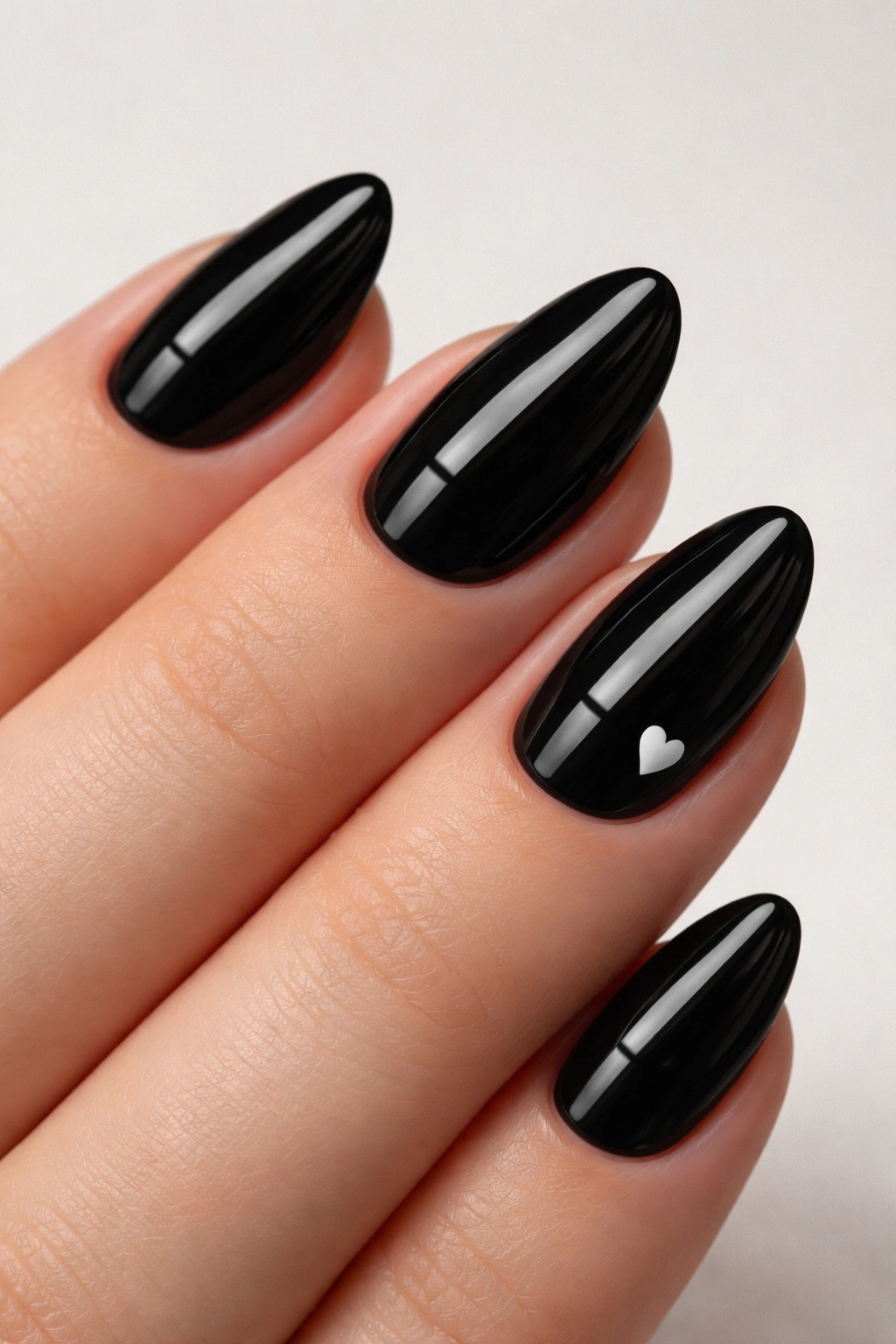 Close-up of a black almond nail with a tiny white heart accent
