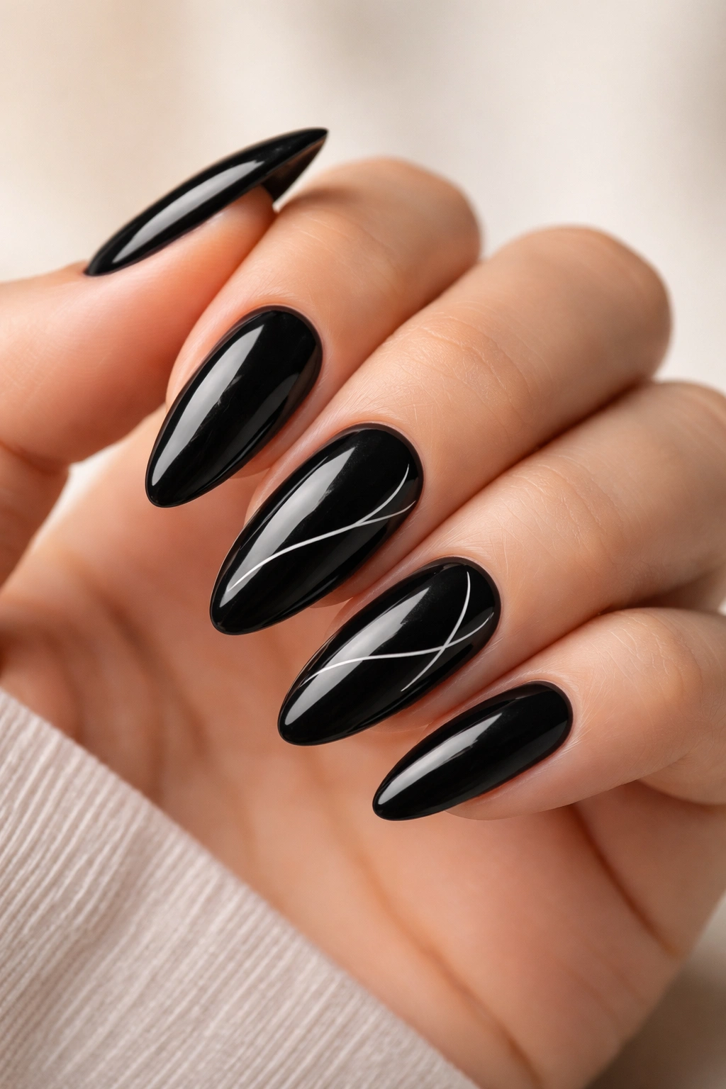 Close-up of black almond nails with minimalist white line art on a glossy finish