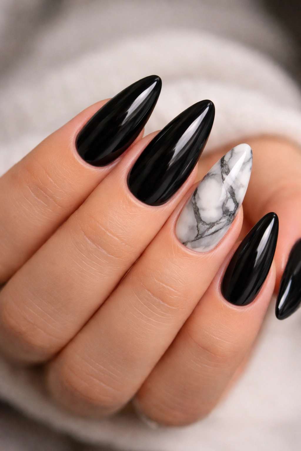 Close-up of black almond nails with marble detail