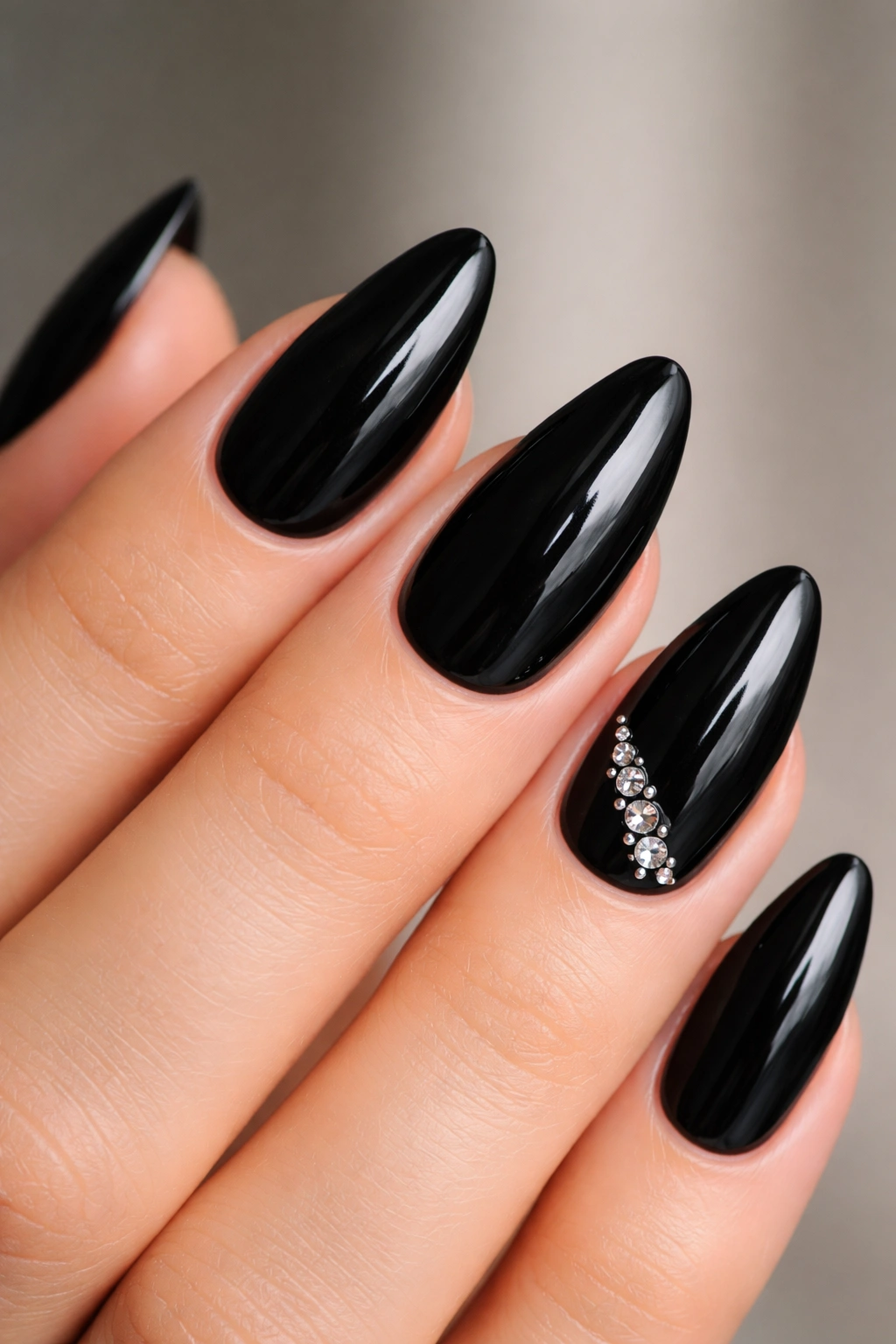 Close-up of black almond nails with tiny rhinestones on one accent nail