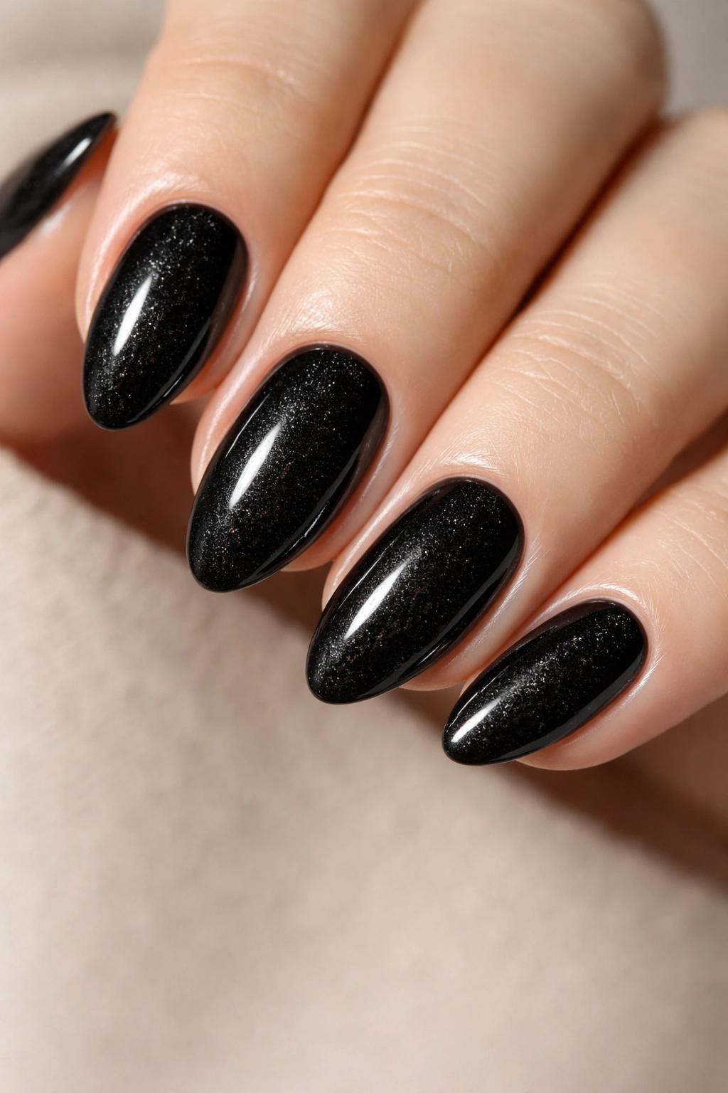 Close-up of black almond nails with subtle shimmer