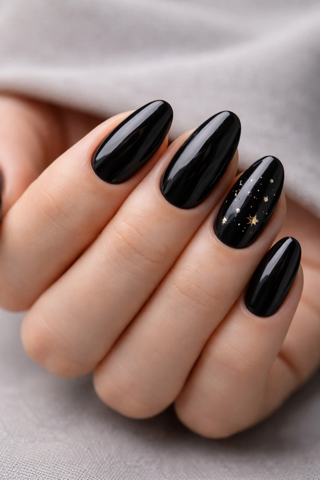 Close-up of black almond nails with tiny star accents.