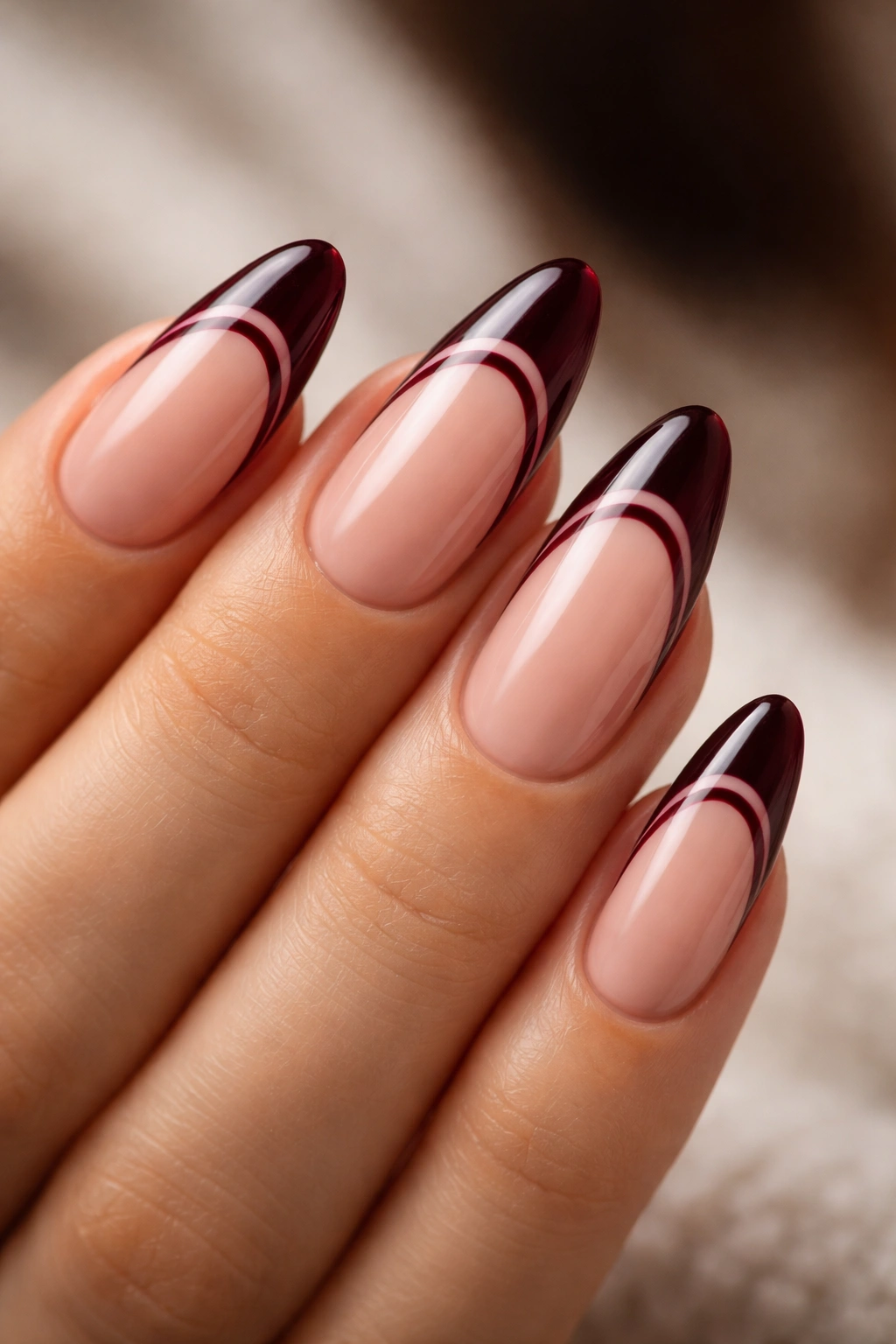 Close-up of almond nails with two black cherry French lines on nude base