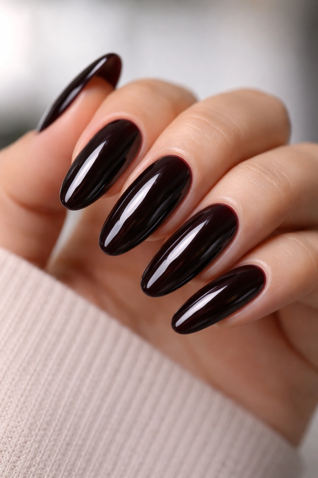Close-up of long oval nails with near-black red-tinged gloss