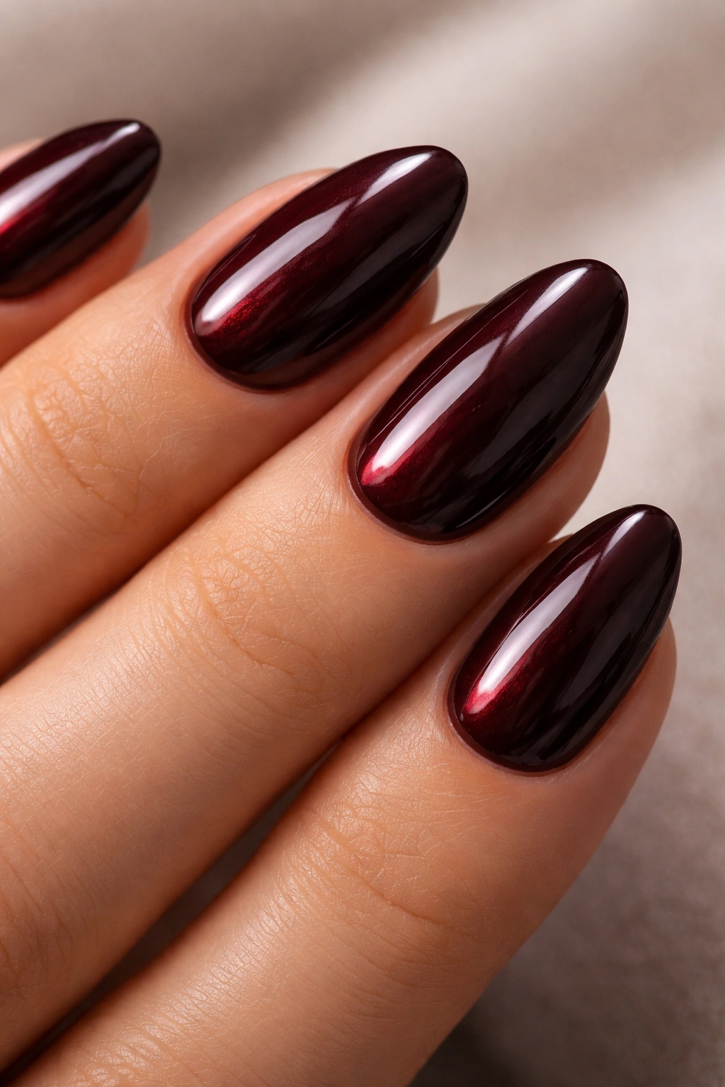 Close-up of short almond nails in black cherry gloss with high-gloss finish