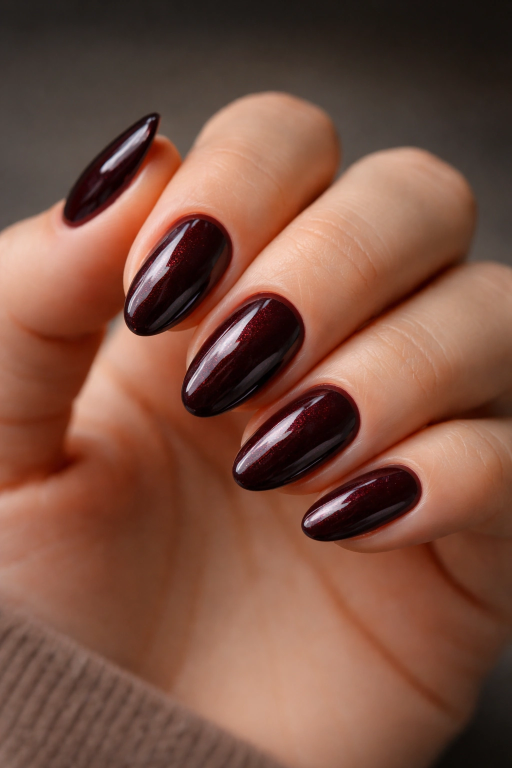 Close-up of deep black cherry almond nails on a hand