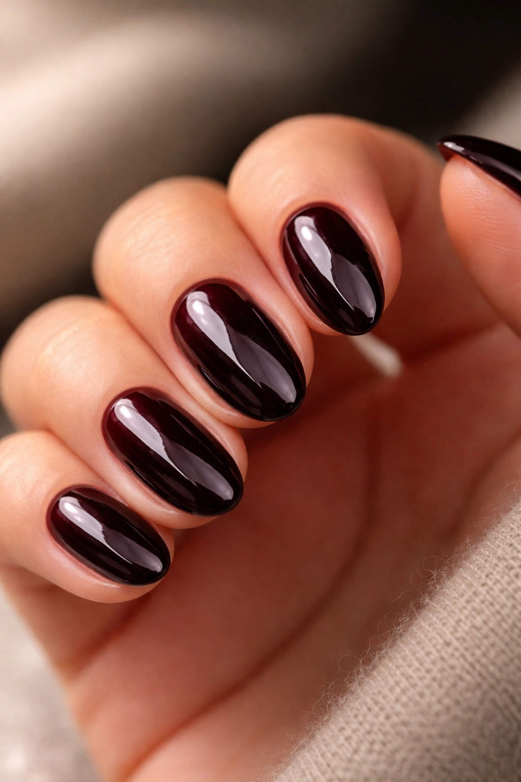 Close-up of short almond nails in deep red-black glossy black cherry finish