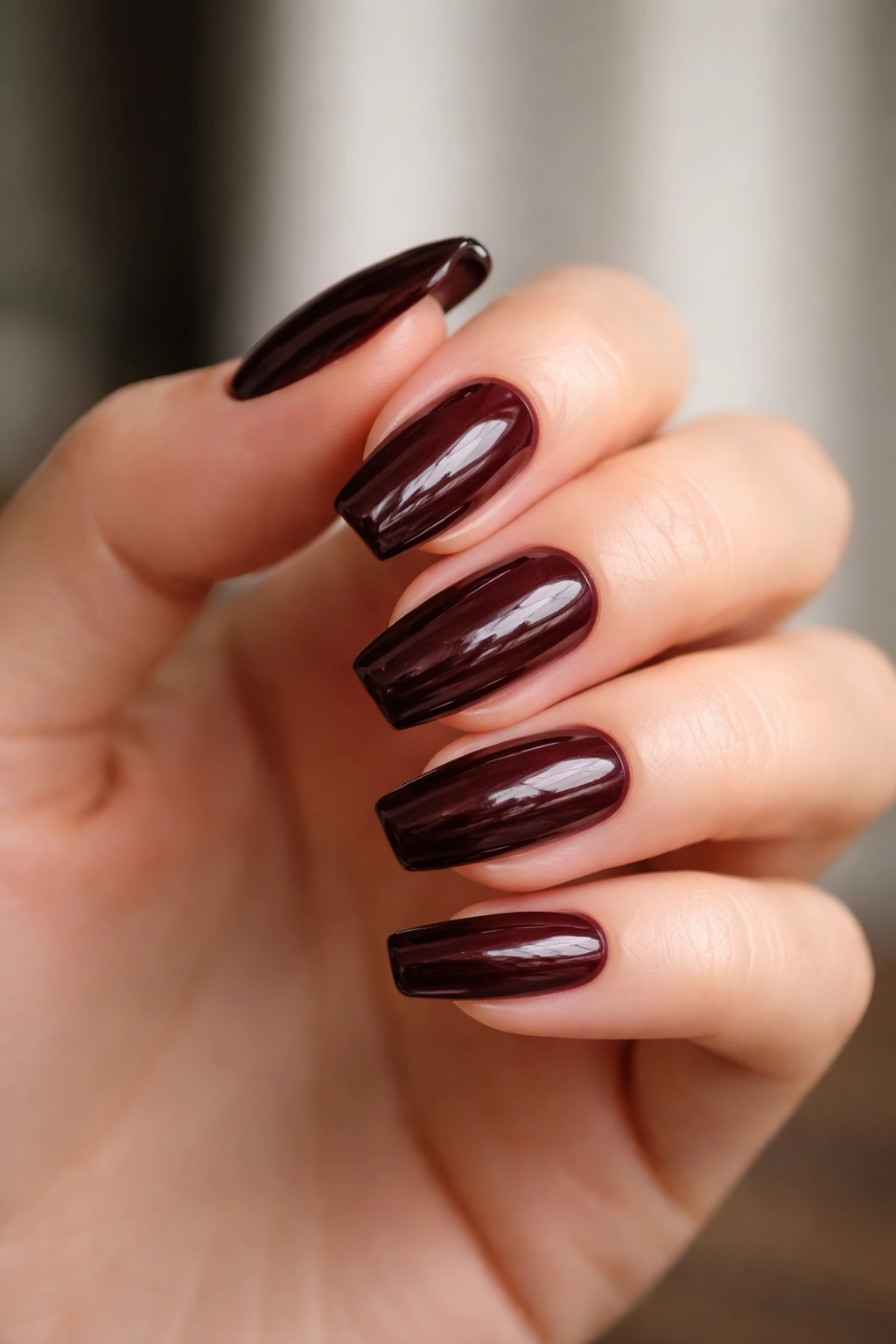 Close-up of black cherry patent nails with a glossy wet-look finish