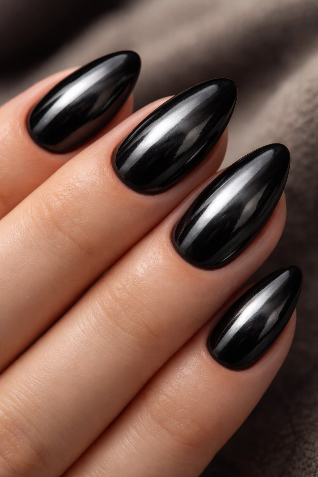 Close-up of black chrome almond nails with smoky reflective finish