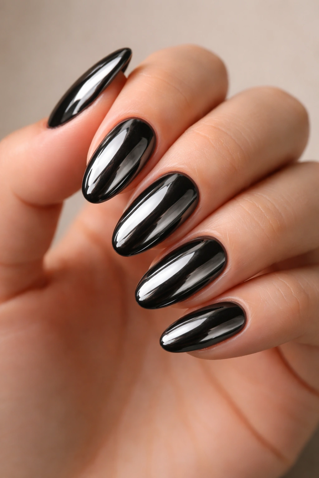 Close-up of glossy jet black chrome short almond nails with mirror finish