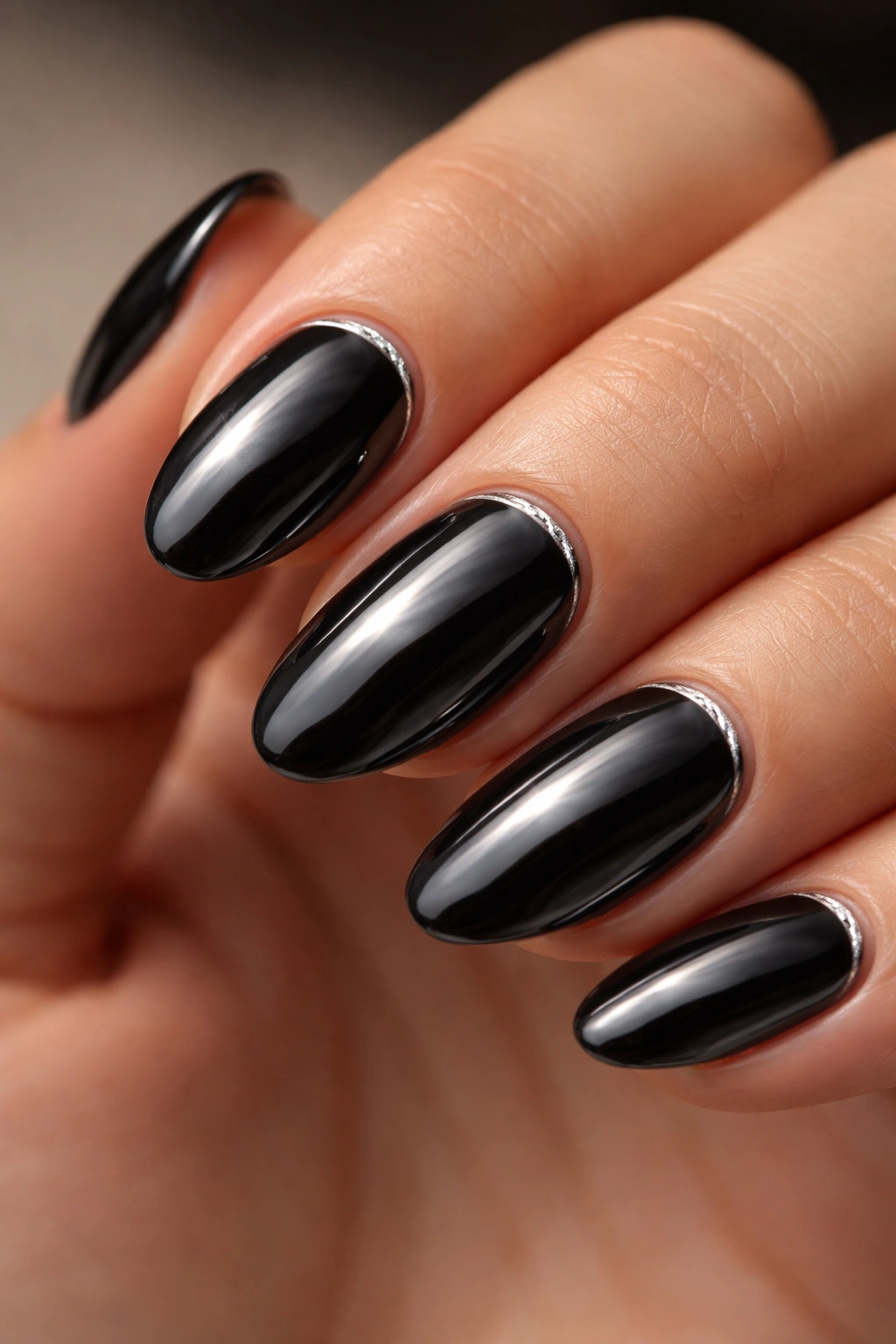 Close-up of black chrome nails with tiny silver cuticle line on almond shape
