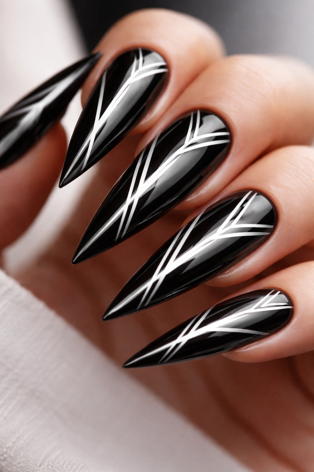 Close-up of black chrome stiletto nails with white geometric lines