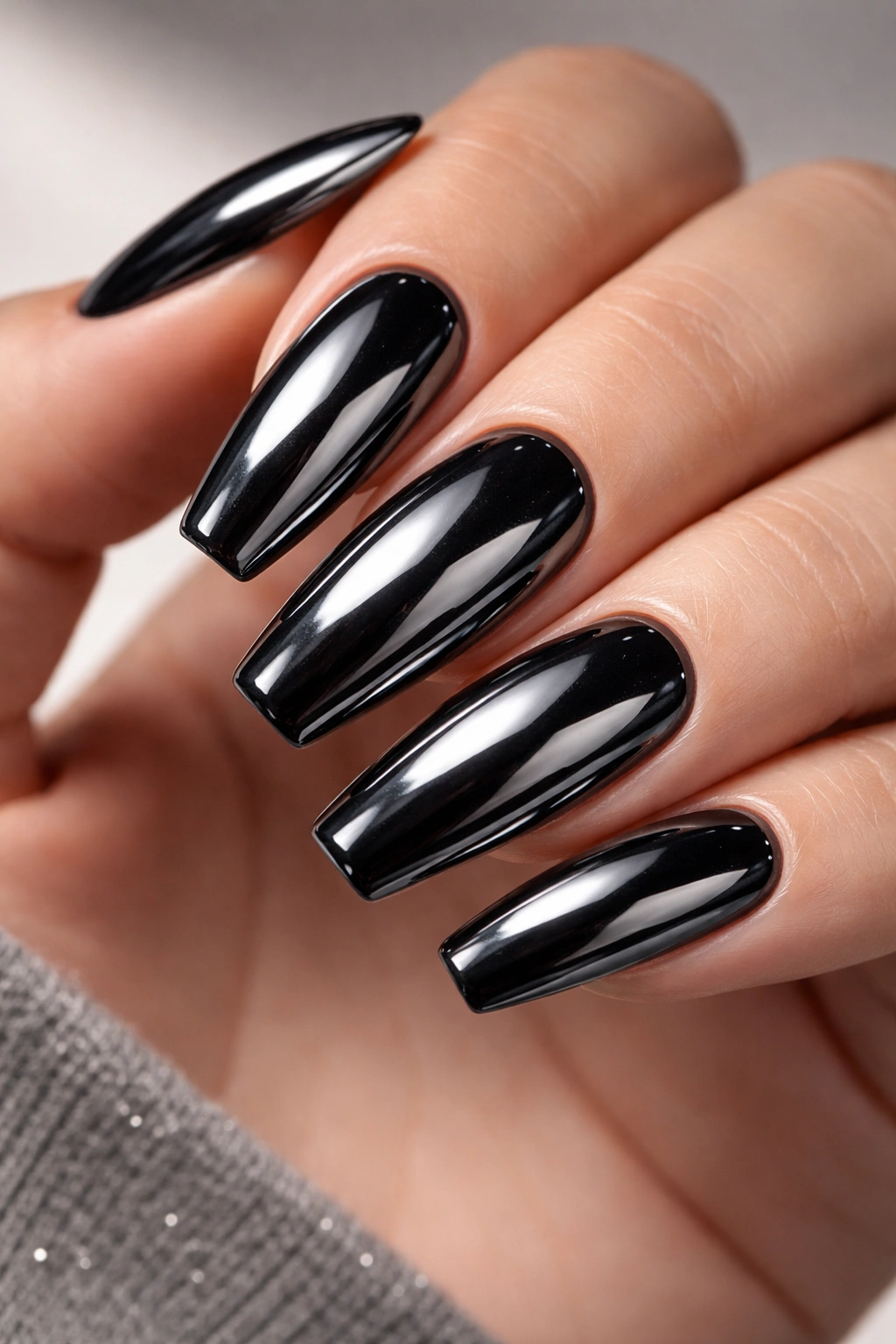 Black chrome nails with reflective mirror finish on a hand