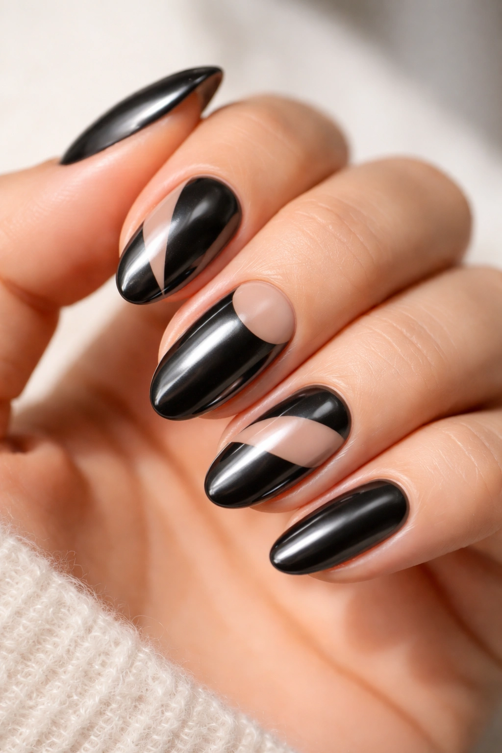 Close-up of black chrome nails with nude negative space on short almond nails