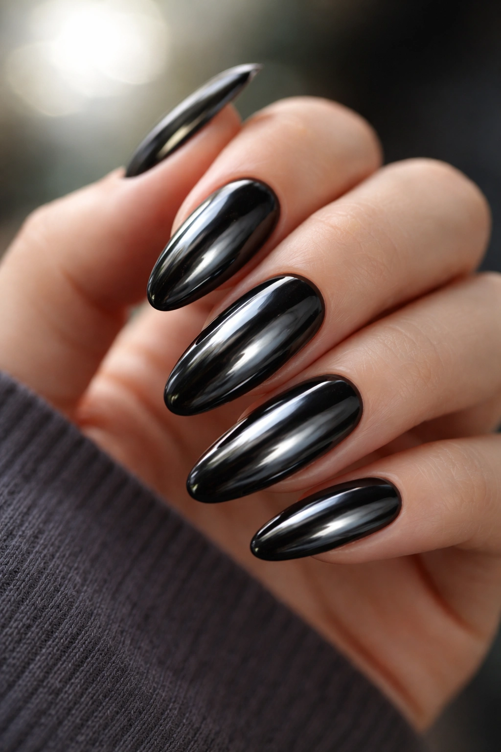 Close-up of black chrome oval nails with reflective finish