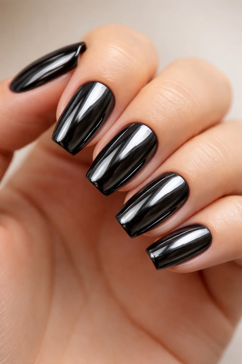 Close-up of black chrome mirror manicure on short ballerina nails
