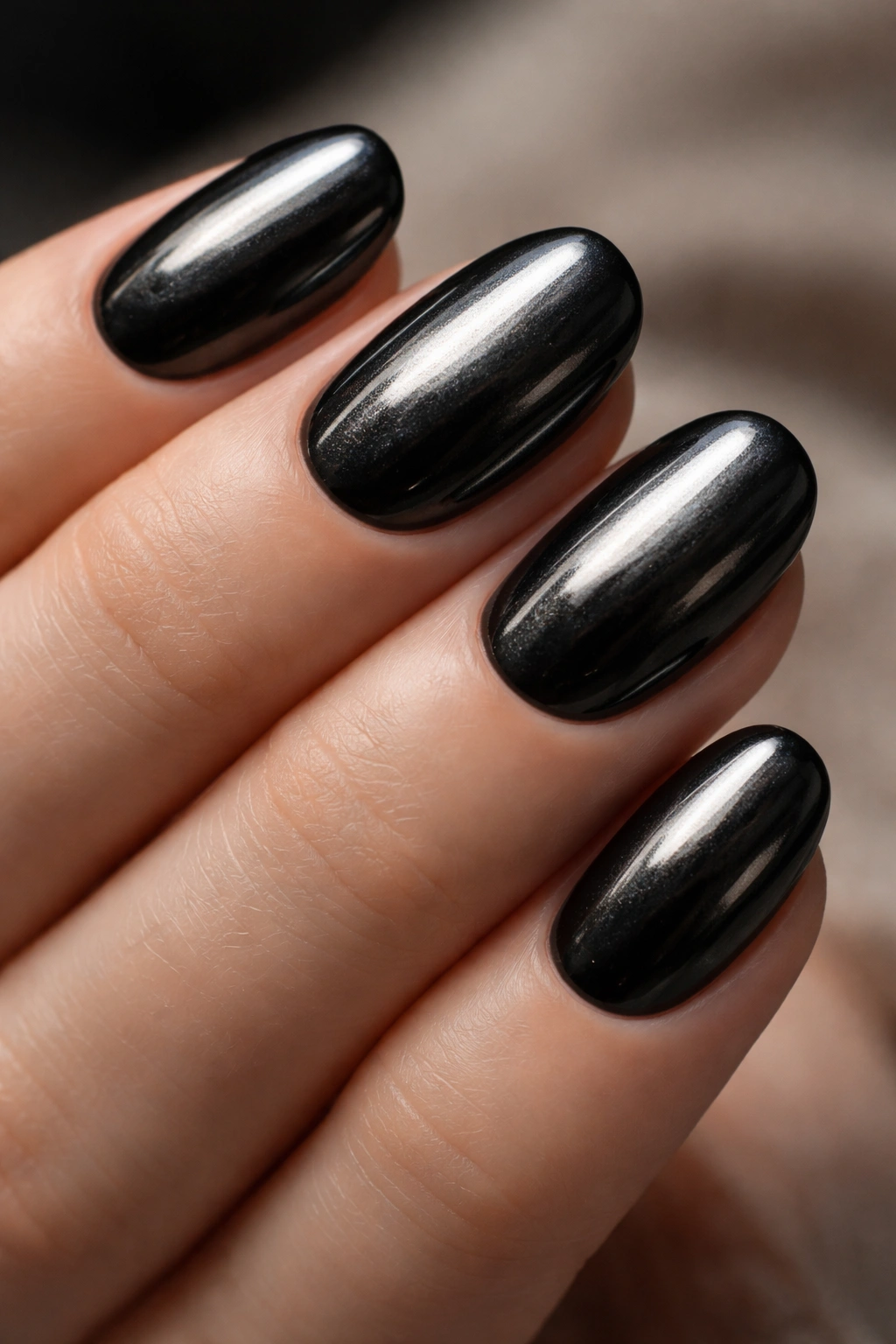 Short oval nails with black chrome overlay on a dark base