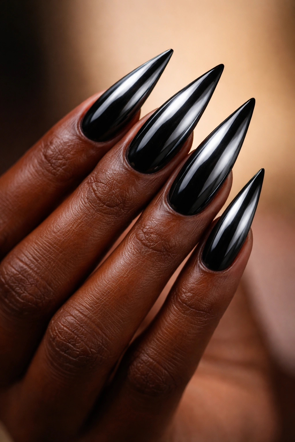 Close-up of black stiletto nails with chrome powder finish.