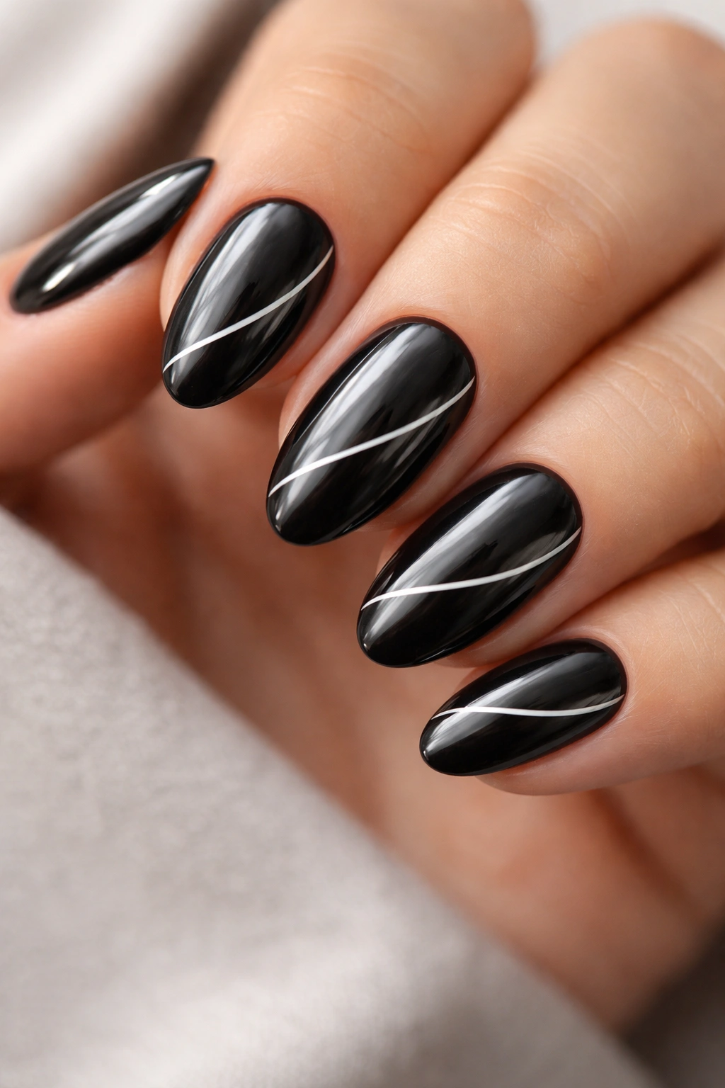 Close-up of black chrome nails with ultra-thin white line art on almond shapes