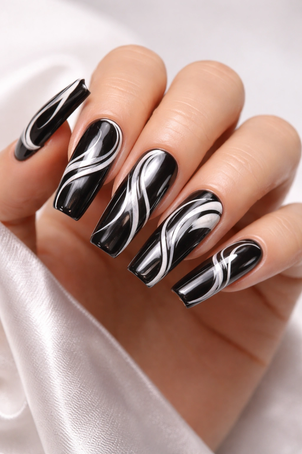 Nails with black chrome base and white negative-space swirls