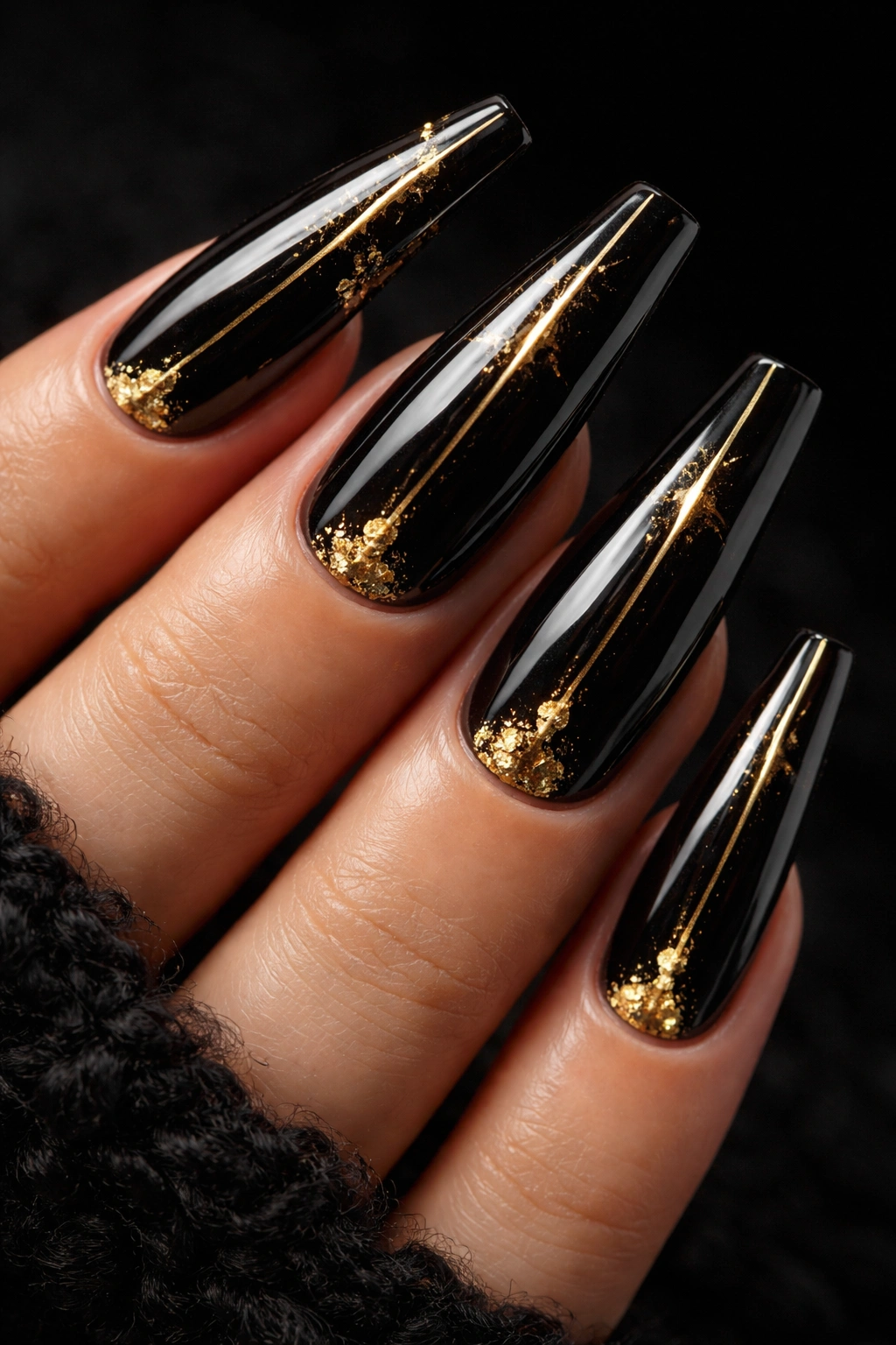 Close-up of black coffin nails with gold accents.
