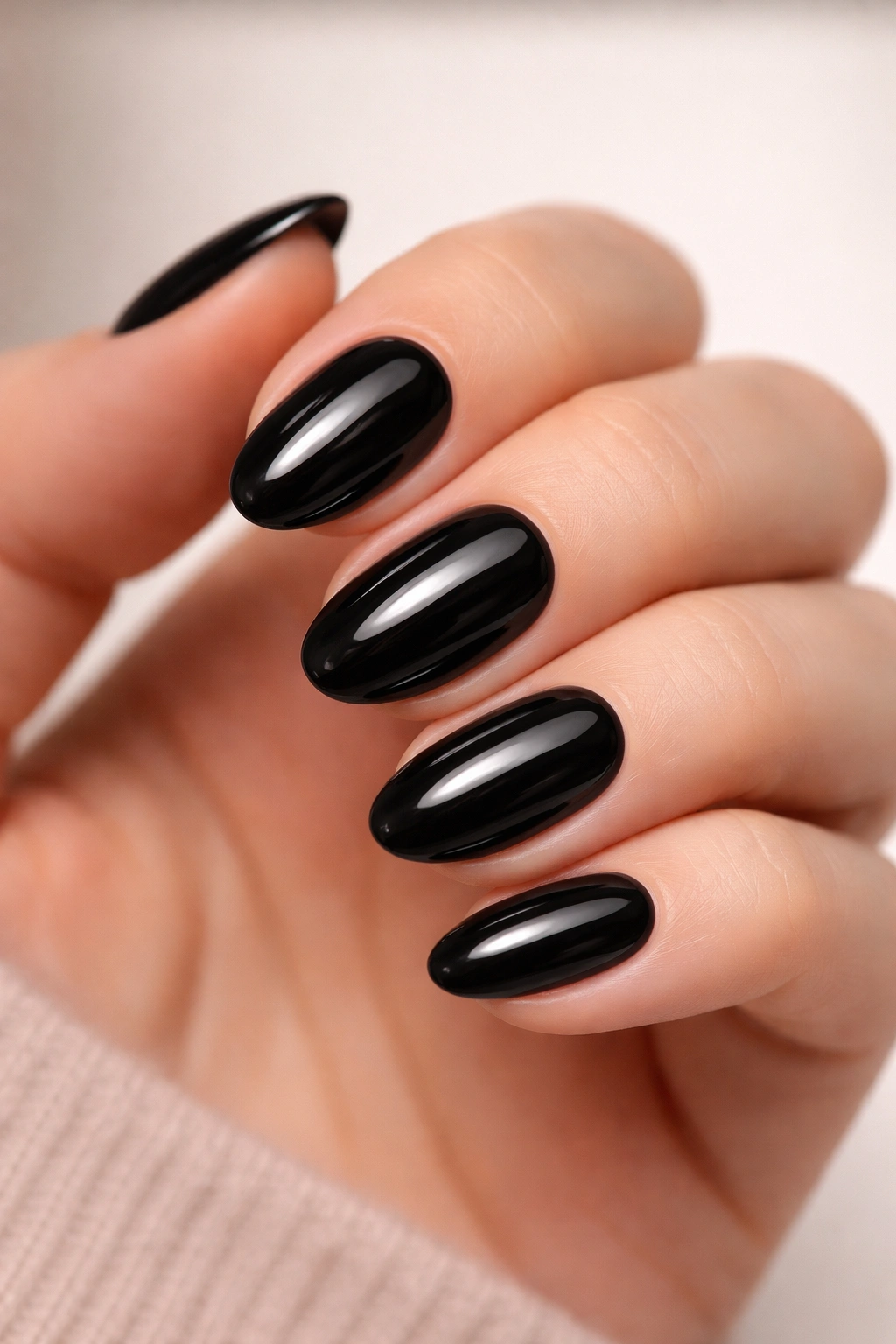 Close-up of black dip almond nails with high-gloss finish and rounded edge