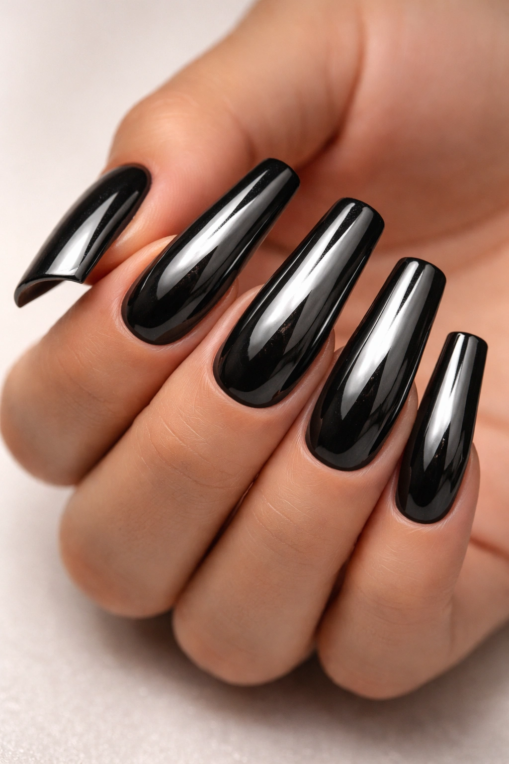 Close-up of black duck nails with chrome/mirror finish showing reflective metallic surfaces.