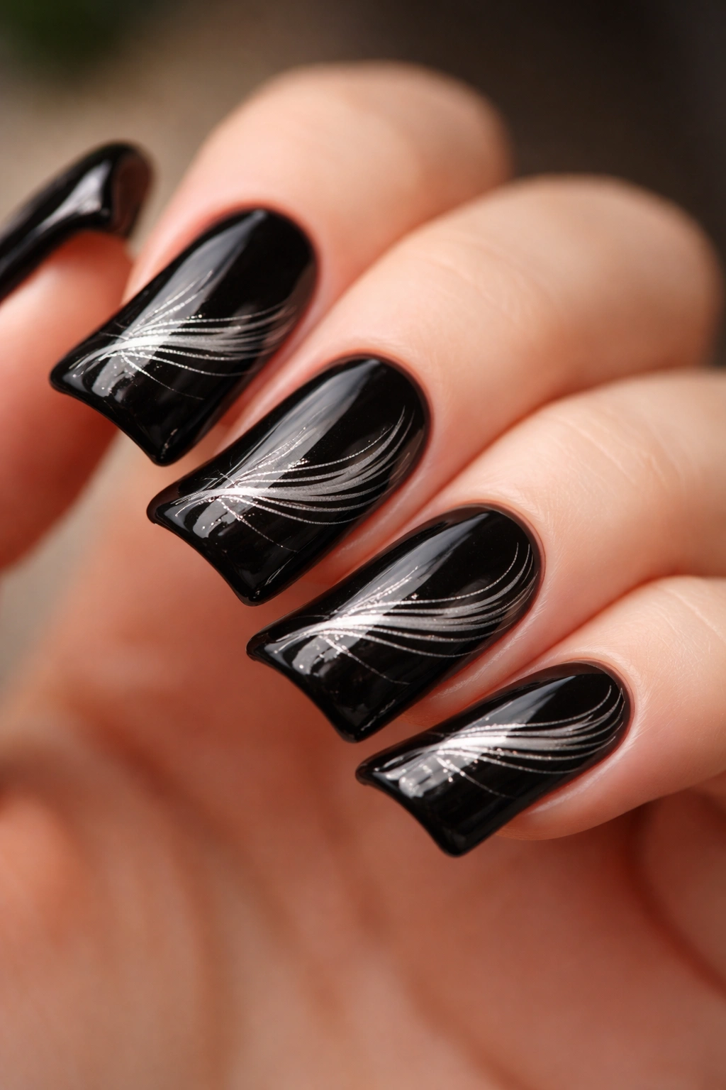 Close-up of black duck nails with fine white and metallic feather detailing