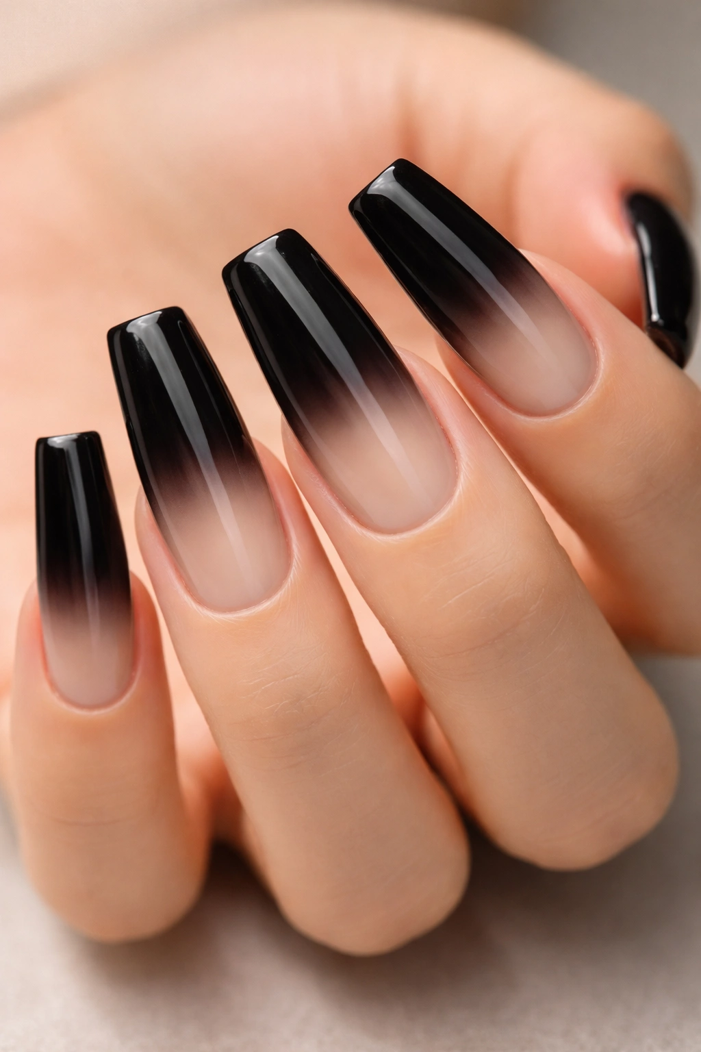 Close-up of black duck nails in an ombre gradient from black to nude.