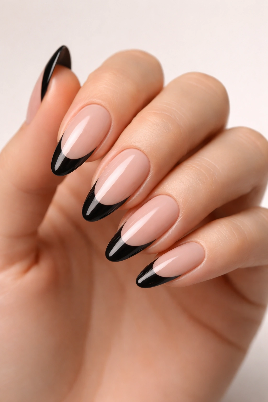 Close-up of almond-shaped nails with black tips on nude base