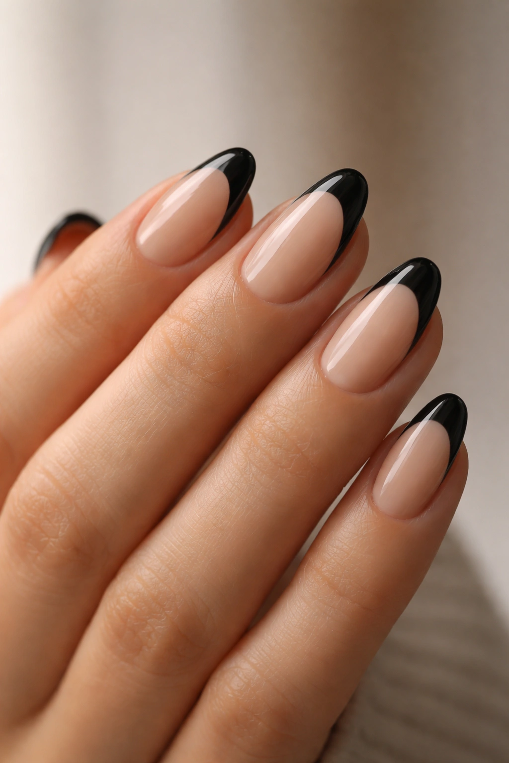 Close-up of black French almond nails on a bare hand