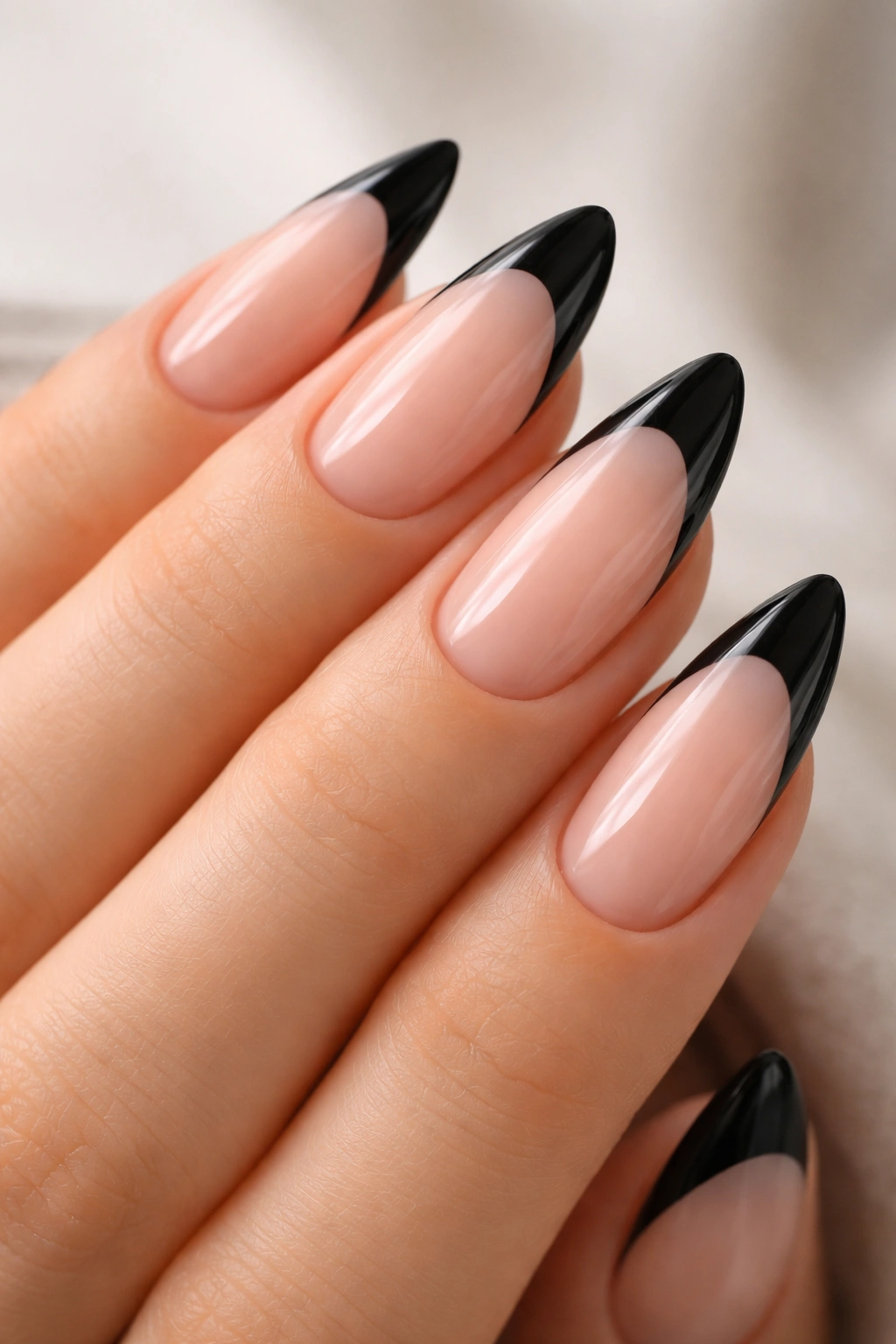 Close-up of almond nails with black French tips on nude base