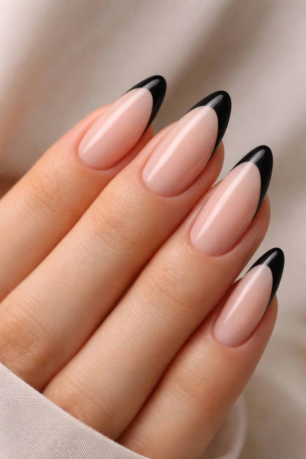 Almond nails with thin black tips on a sheer nude base.