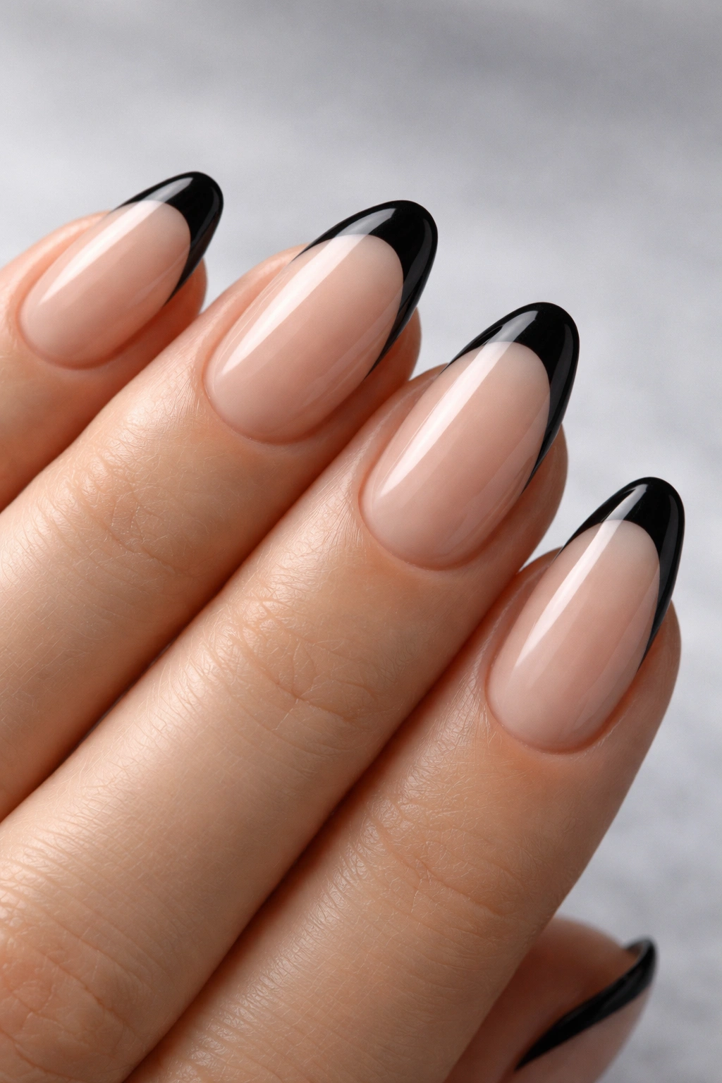 Close-up of nude almond nails with black French tips