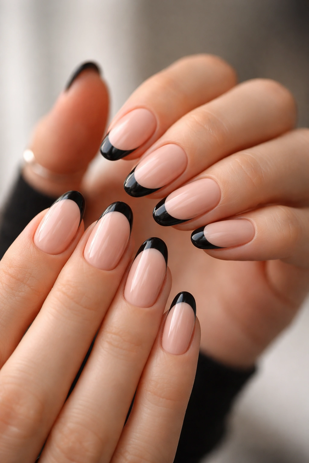 Close-up of hands with black French tips on short almond nails