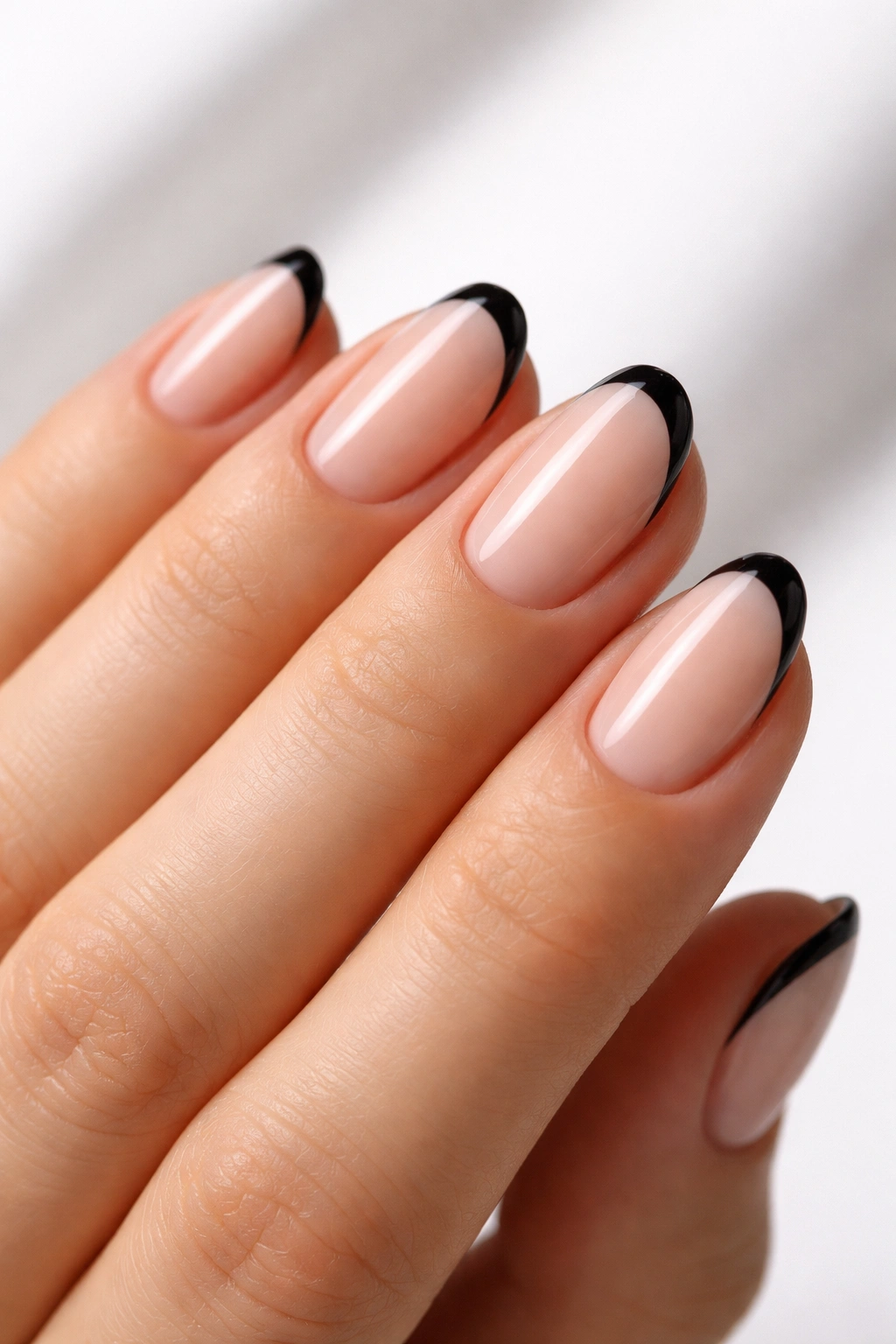 Close-up of short oval nails with slim black tips on nude base