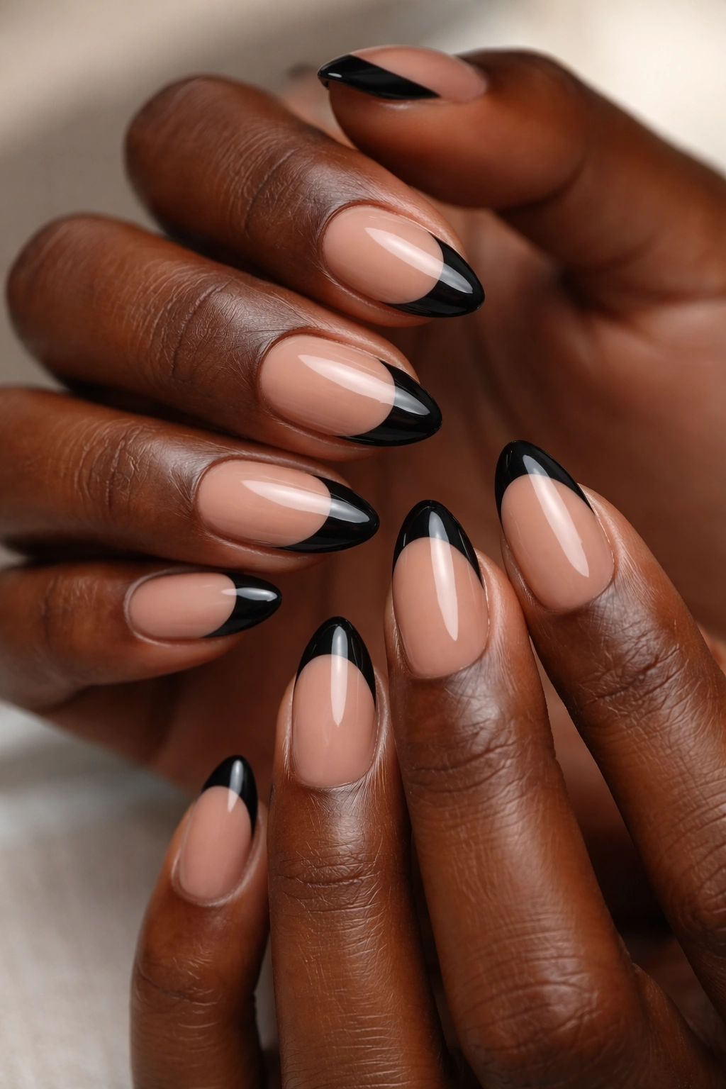 Close-up of black French tips on nude base almond nails on dark skin