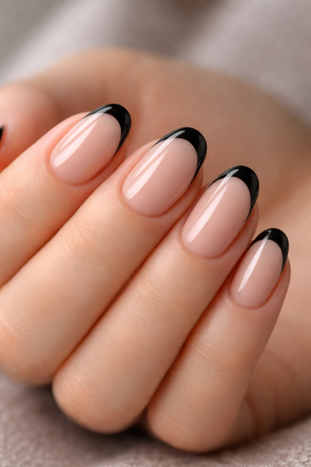 Close-up of short oval nails with black French tips on a sheer nude base