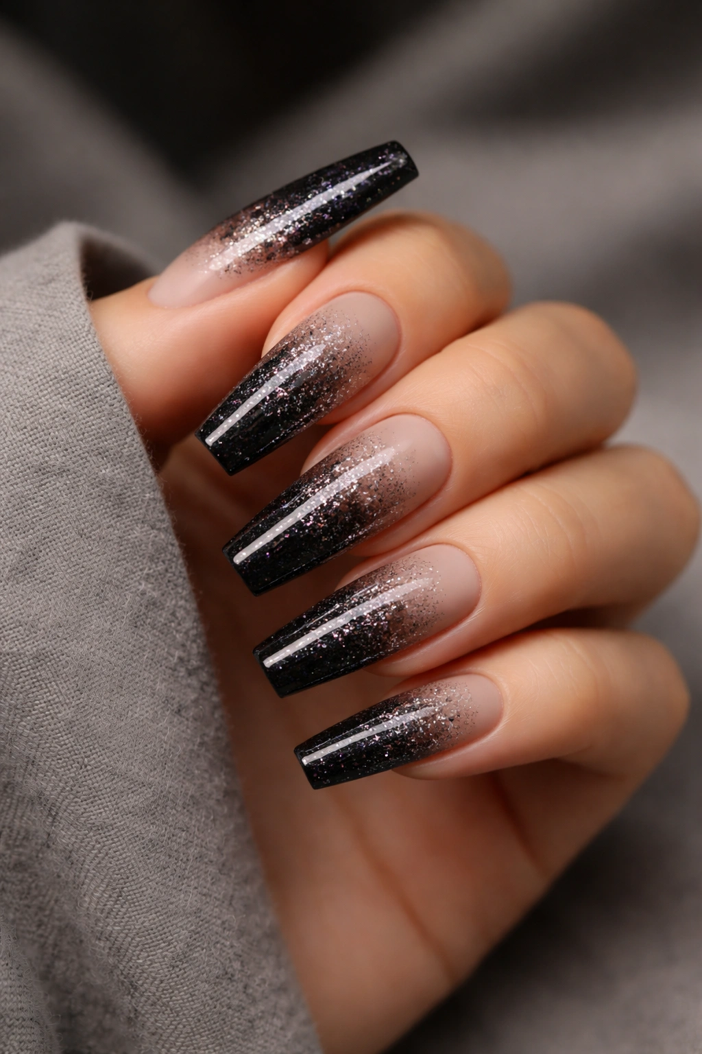 Long coffin nails with black glitter gradient fading to nude near the cuticle.