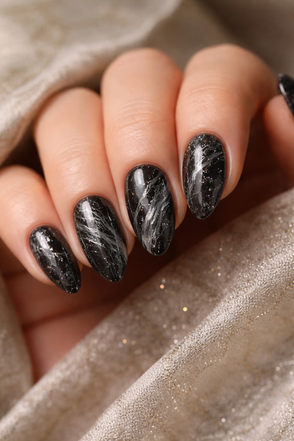 Short almond nails with black marble pattern and subtle glitter