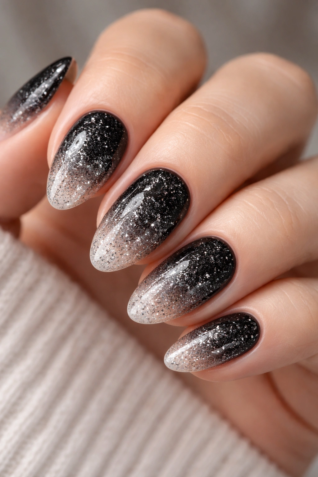 Close-up of short almond nails with black glitter ombré gradient