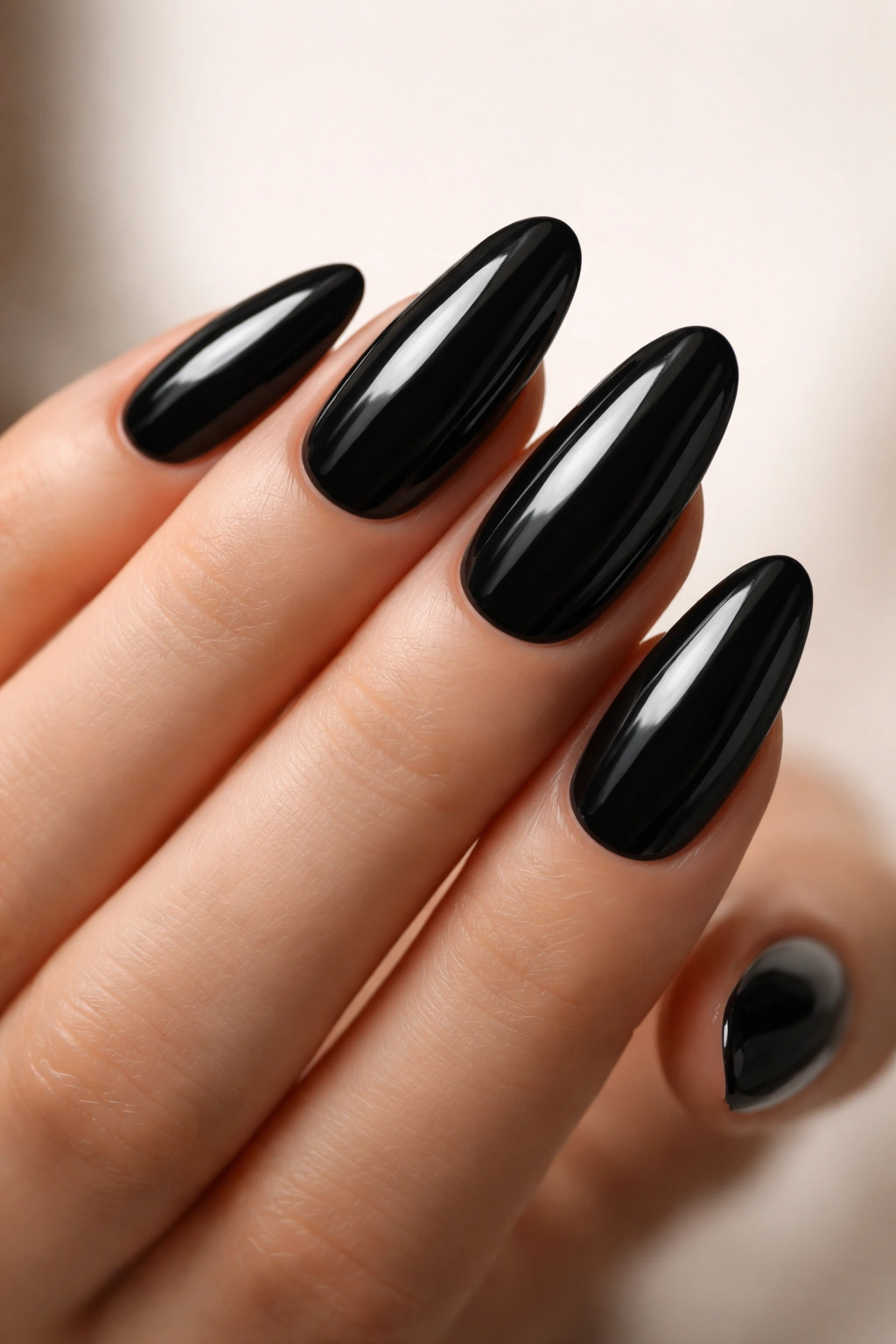 Close-up of glossy black long oval nails with a smooth reflective surface