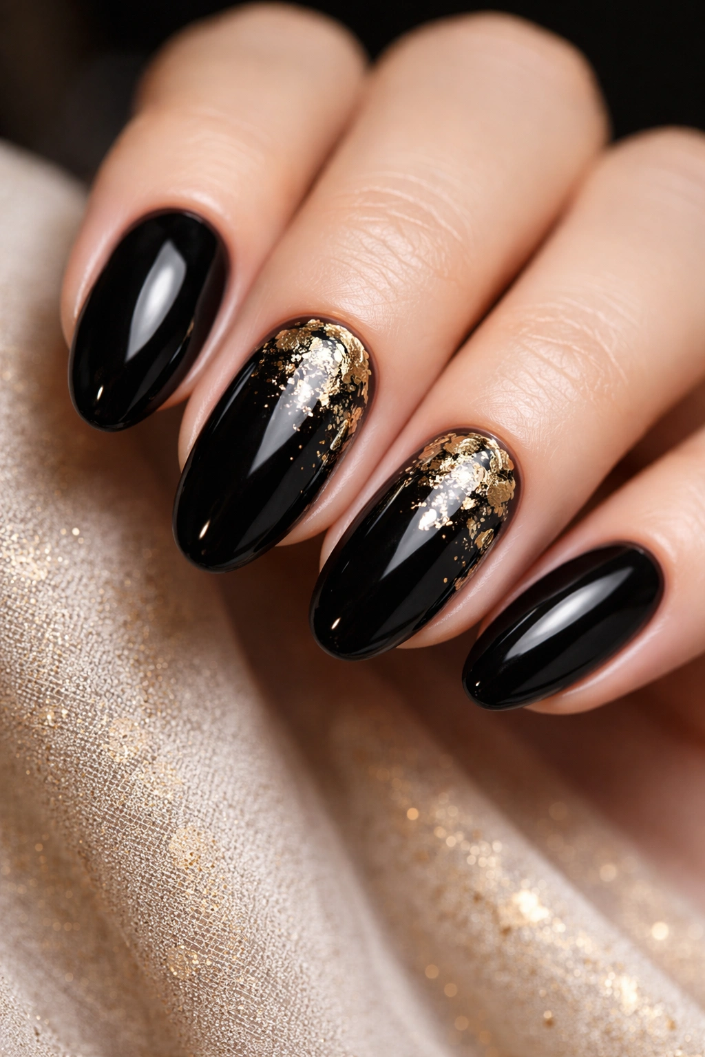 Close-up of black nails with gold foil details on an accent nail