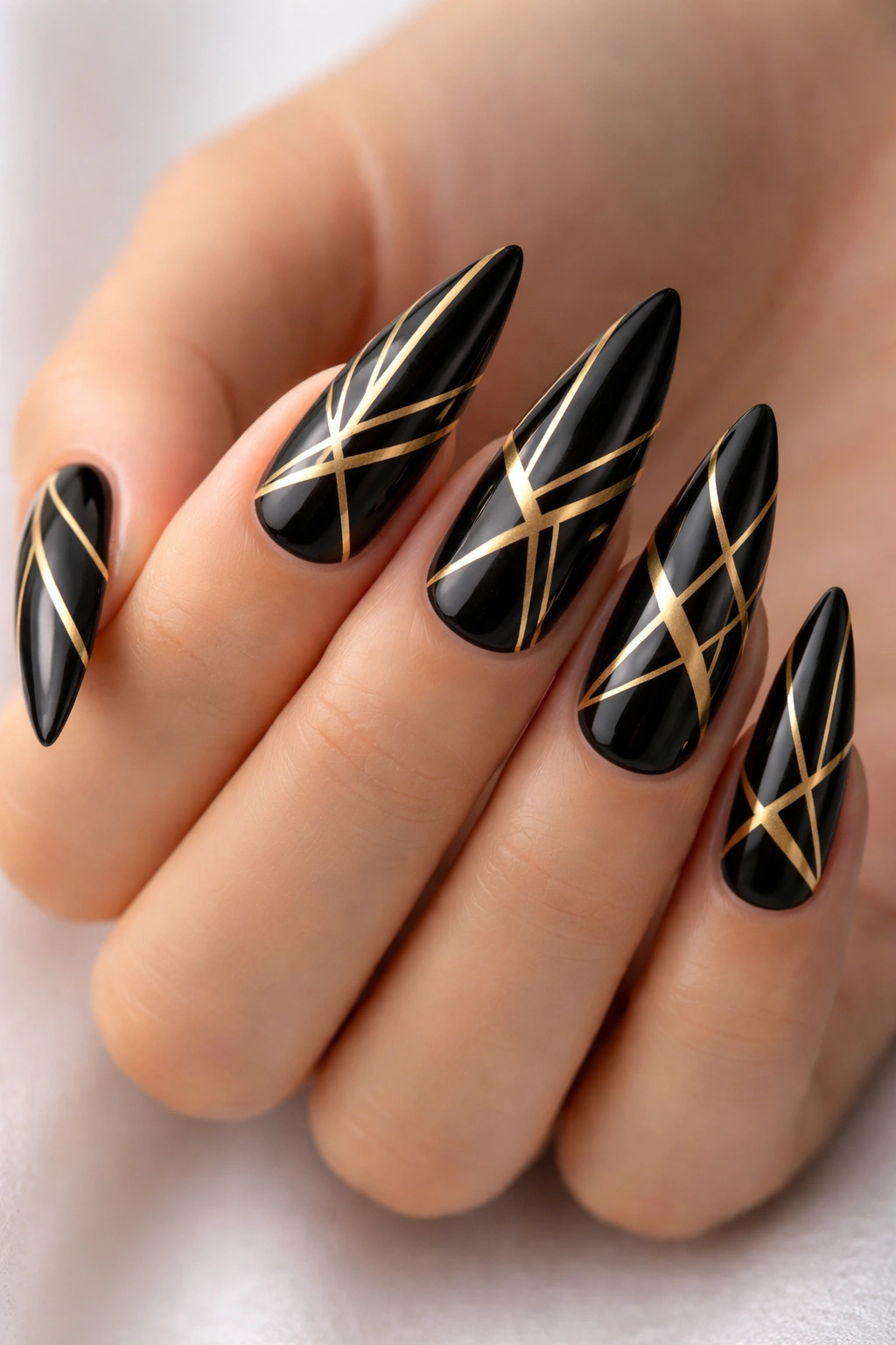 Close-up of black stiletto nails with precise gold geometric lines