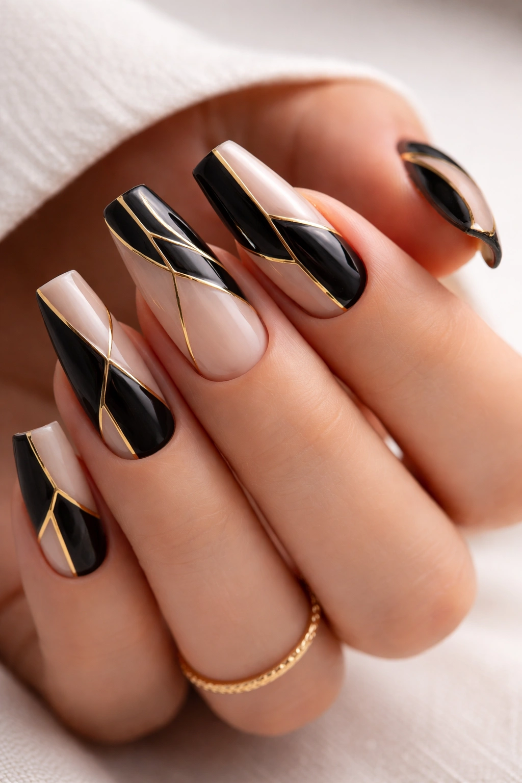 Close-up of black and gold geometric ballerina nails on a nude base
