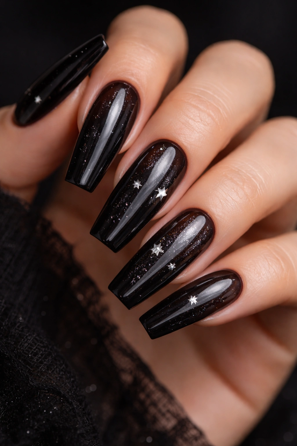 See-through black jelly nails with embedded silver stars and a glassy finish