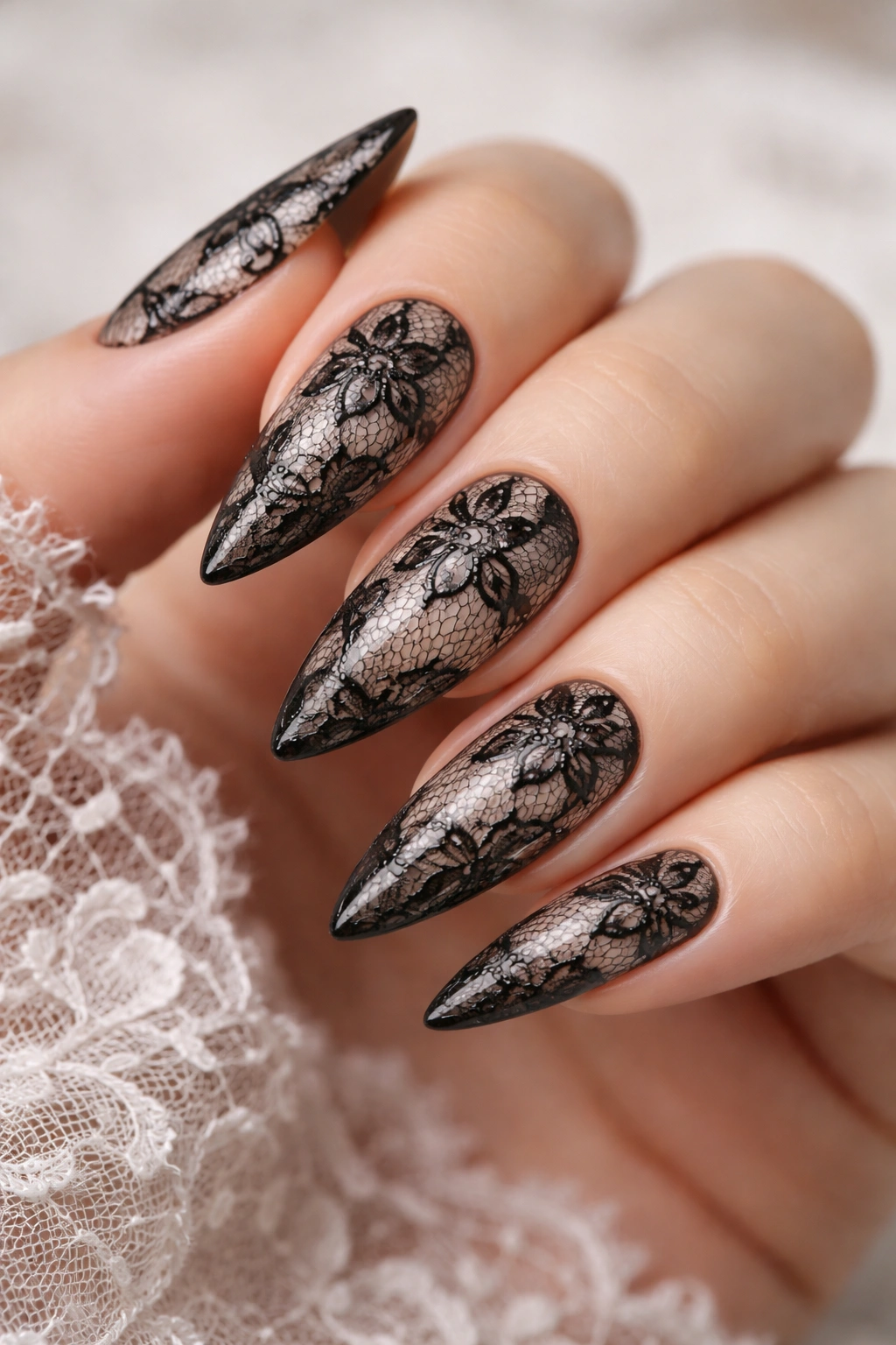 Close-up of black lace nails on nude base with intricate lace patterns