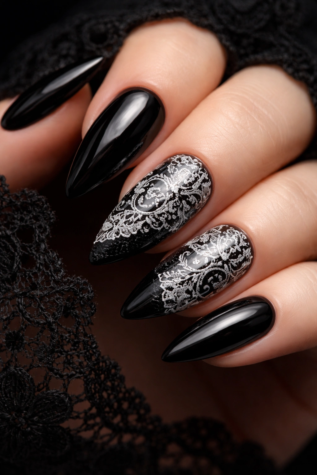 Black nails with white lace stamping pattern on a clean background.