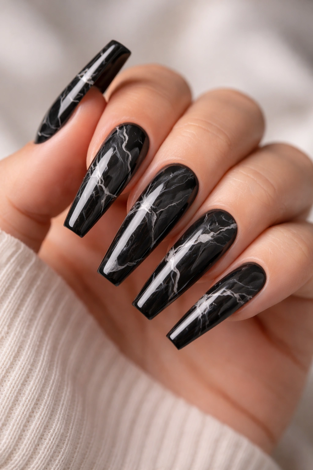 Close-up of black marble coffin nails with white veining on a hand