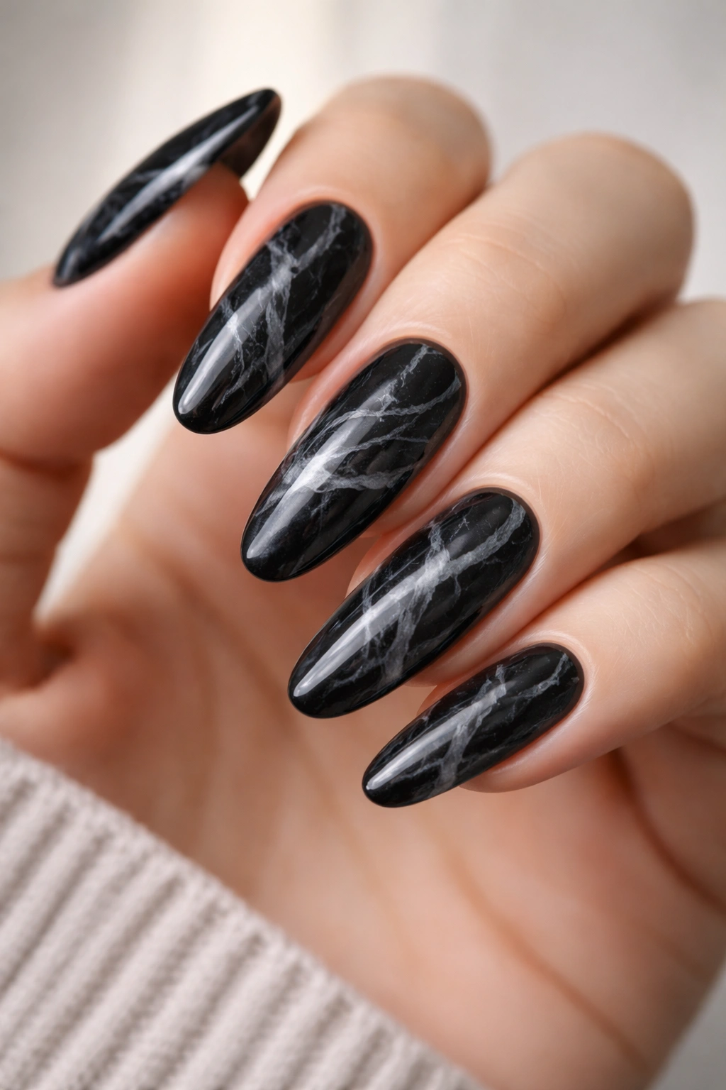 Close-up of black marble long oval nails with thin white and gray veining